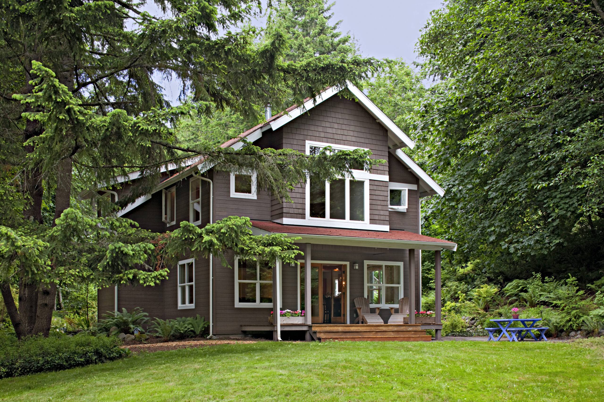 Brown modern traditional country home with green lawn and trees.