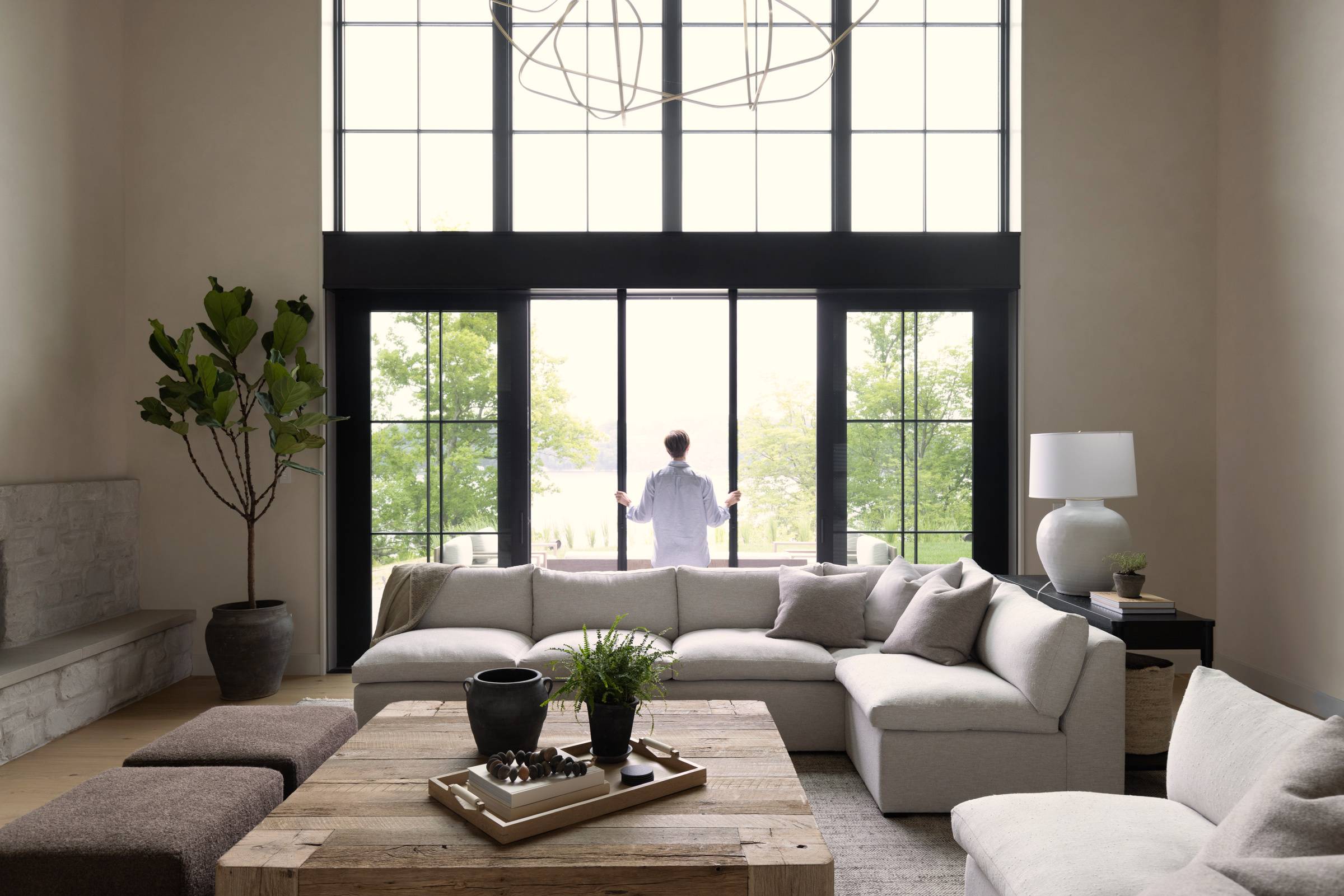 Home interior with white couch, large floor to ceiling picture window, and a person opening patio doors.