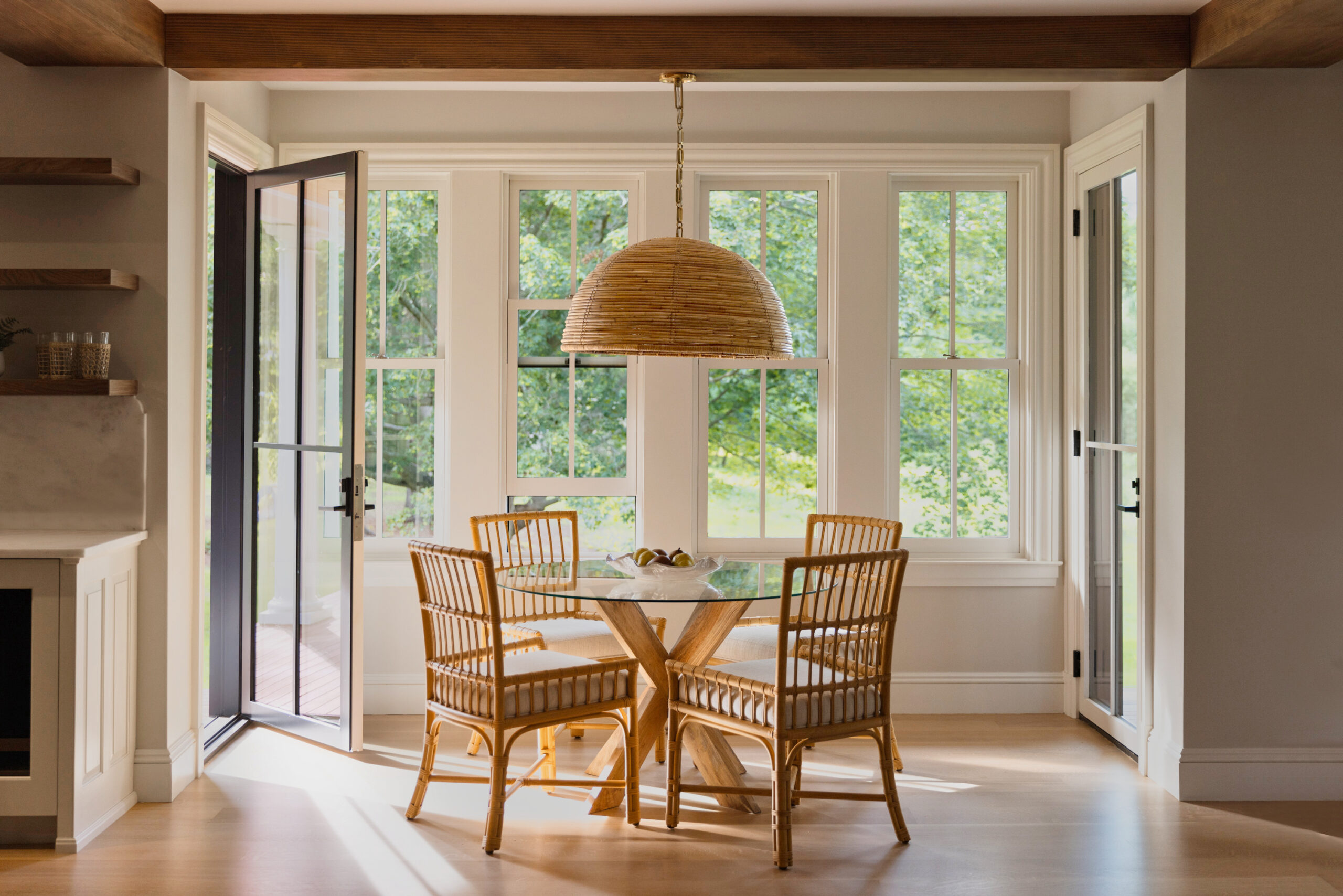 Open dinning room with warm wood accents, and large sliding picture windows and glass patio door.