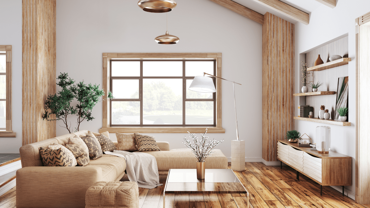 Living room with tan couch, light wood rustic accents, and large window with light wood trim.