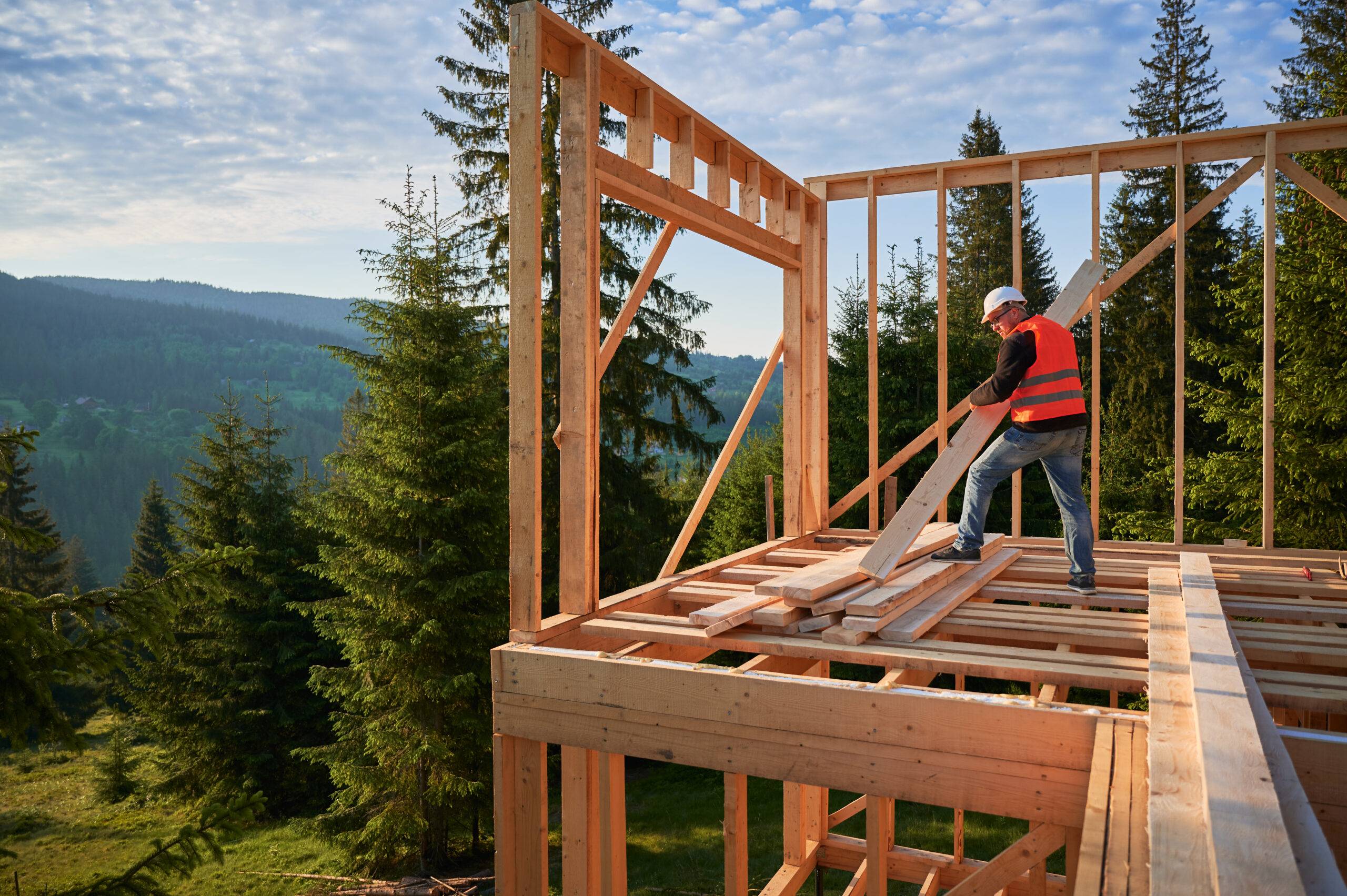 Carpenter building timber frame for a house in the woods.